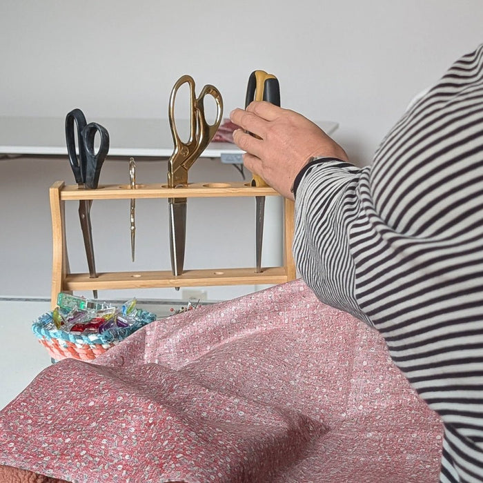 women grabbing fabric scissors on a craft table from a wooden scissor stand