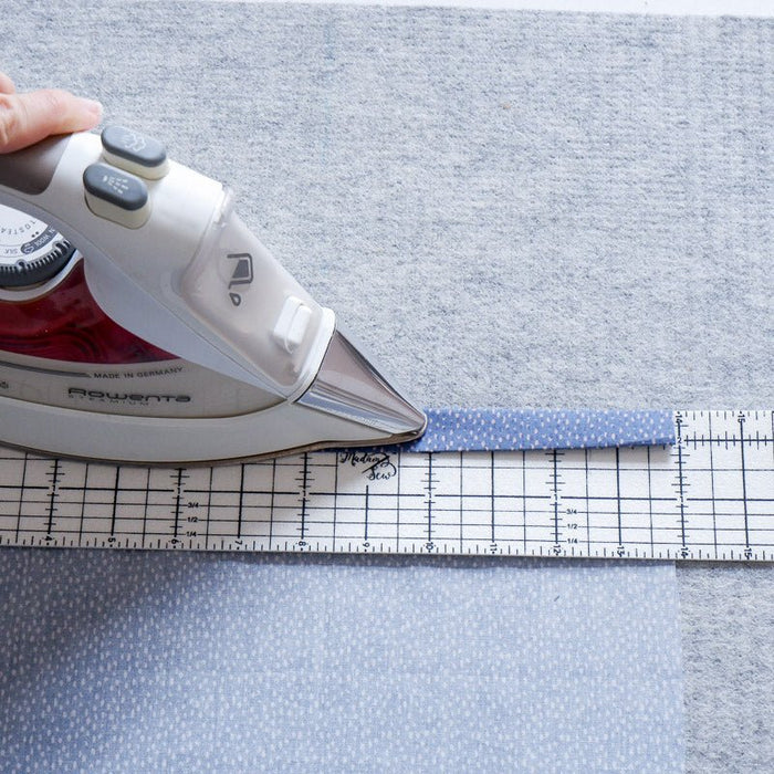 Someone uses a hot hem ruler  and iron to iron a hem on dotted fabric